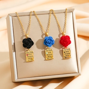Three velvet rose pendant necklaces in red, blue, and black with engraved gold square tags