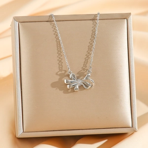 Elegant 18k silver bow pendant necklace with zircons displayed in a luxury jewelry box