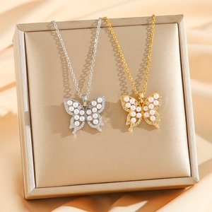 Elegant 18k gold and silver butterfly necklaces with pearls and zircons on a display box