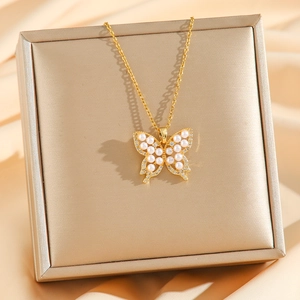 Elegant 18k gold butterfly pendant necklace with pearls and zircons on silk background