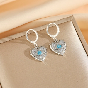 Gros plan de boucles d'oreilles en cœur avec pavé de cristaux et motif fleur bleue