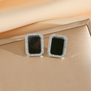 Détails macro de boucles d'oreilles noires rectangulaires serties de zircons