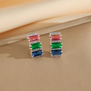 Detail view of silver earrings with tiered pink, green, and blue zircon gemstones