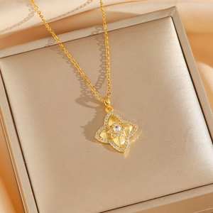 Elegante collana a quadrifoglio dorata con stella in zircone su sfondo di seta di lusso