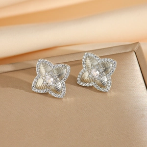 Dettaglio degli orecchini a fiore in argento con zirconi e texture in metallo spazzolato