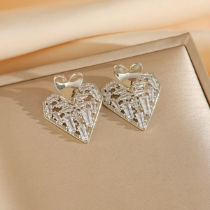 Macro shot of silver heart earrings with pavé cubic zirconia on soft satin background