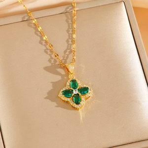 Golden clover pendant necklace with emerald green stones and diamond accents