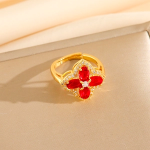 Macro shot of gold floral open ring featuring red oval gemstones and pavé crystals
