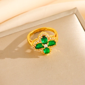 Macro detail of gold-plated clover ring featuring green emerald-like stones and crystals