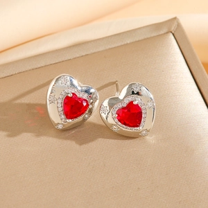 Détail macro de boucles d'oreilles en cœur avec pierre rouge et relief d'étoile