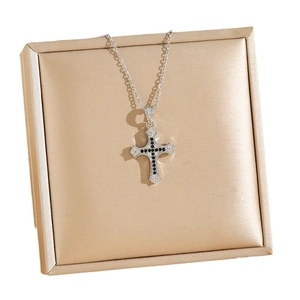 Cross pendant necklace with white and black zircons on a gold textured jewelry box
