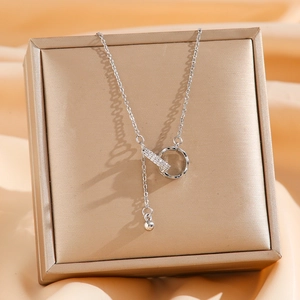Silver interlocking circle and cubic zirconia bar Y-necklace on a gold jewelry box