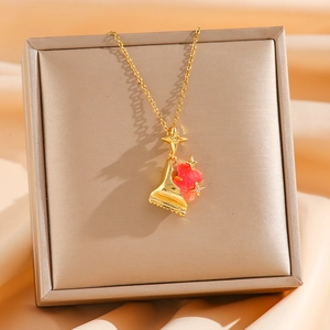 Detailansicht der goldener Klavier- und rosa Wolken-Anhänger an der Halskette
