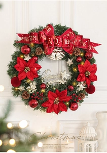 Detail of a lighted Christmas wreath with red poinsettias, golden bells and velvet bow