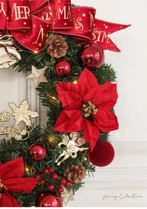 Close-up of lighted Christmas wreath with red flowers, pine cones and gold ornaments