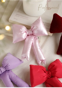 Detailed close-up of padded fabric bows in pink, purple, and red for Christmas decor