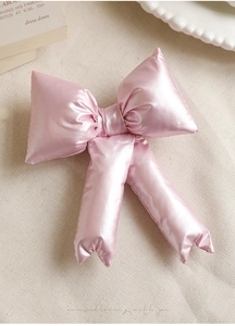 Macro shot of a puffy pink bow decoration with satin finish on a neutral textured background