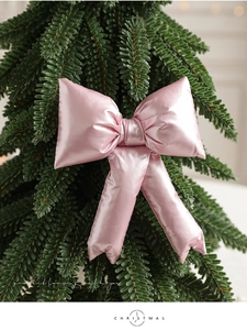 Close-up of a pink satin bow ornament on green Christmas tree branches