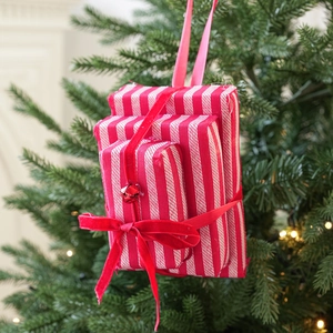Detail of red and white striped stacked gift box ornament with velvet bow on Christmas tree
