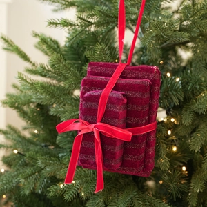 Detail of red velvet Christmas gift box ornaments hanging on a warm lit Christmas tree