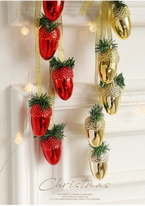 Detail of red and gold Christmas acorn ornaments with festive ribbons on a white wall