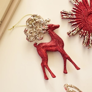 Detail shot of a red and silver glitter reindeer Christmas ornament with golden hanging cord