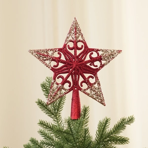 Detail of red glitter Christmas star tree topper with intricate cutout gold patterns