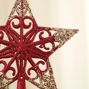 Detail of red hollow-out star Christmas tree topper with gold glitter floral patterns