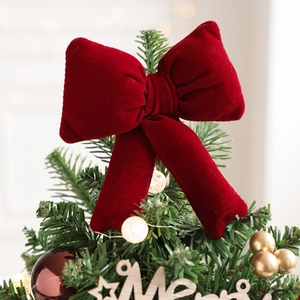 Velvet red Christmas tree topper bow with festive ornaments and warm light decorations