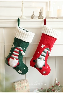 Detail of plush Christmas stockings with gnome embroidery hanging on a white fireplace