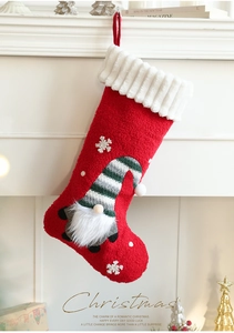 Detail of red plush Christmas stocking with 3D gnome and snowflake embroidery on mantel