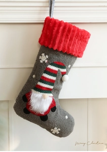 Detail of plush grey Christmas stocking with a 3D gnome and red ribbed cuff decoration