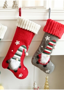 Close-up of knit Christmas stockings with plush gnomes and snowflake details on a mantel