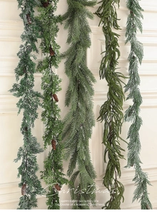 Vertical display of Christmas pine garlands with pine cones on a classic white wall