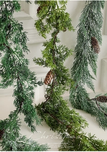 Detail of frosted pine garland with snow effect and pine cones against a white wall