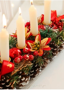 Detail of Christmas candle holder with white pillars, pine cones, and red berries decor