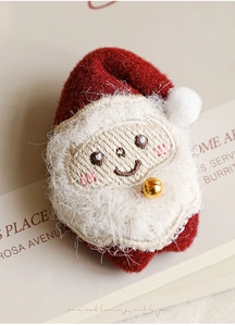 Dettaglio di un babbo natale di peluche con cappello rosso e campanellino dorato su libro