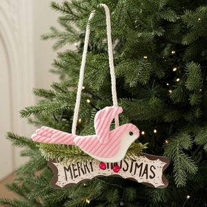 Close-up of a pink fabric bird on a Merry Christmas wooden sign with pine needles