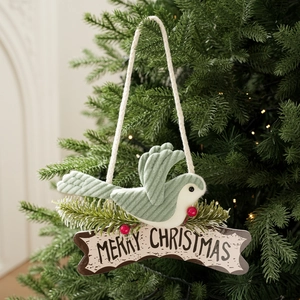 Detail of green corduroy bird ornament with Merry Christmas sign on a glowing festive tree