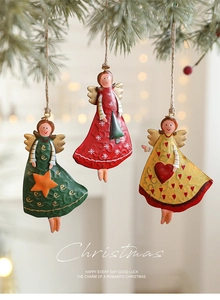 Close-up of three vintage metal angel ornaments hanging on green Christmas tree branches