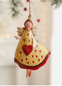 Macro view of vintage iron Christmas angel ornament with red heart on a pine branch