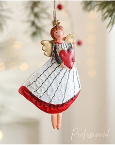 Detail of vintage metal angel ornament with red heart hanging on a festive Christmas tree
