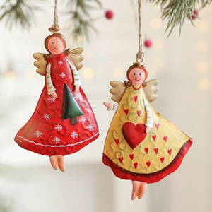 Vintage iron Christmas angel ornaments hanging on a pine branch with festive berries