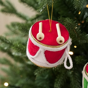 Roter und weißer Weihnachtstrommel-Anhänger mit Schlägeln an einem grünen Christbaum