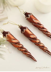 Close-up of three bronze icicle Christmas ornaments with gold glitter and hanging strings