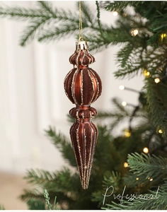 Detail of dark brown flocked Christmas ornament with gold glitter stripes on tree branch