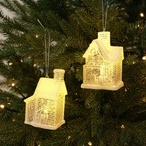 Close-up of glowing transparent Christmas house ornaments with LED light on a pine tree