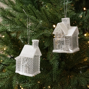Close-up of clear Christmas house ornament with snow textures on a lit festive tree