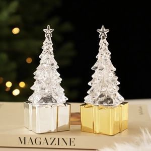 Close-up of crystal Christmas tree figurines with metallic gold and silver gift box bases