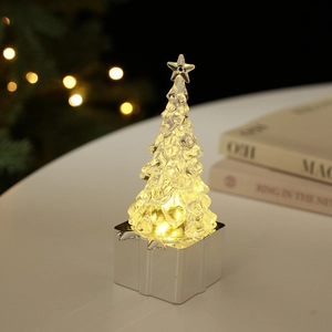 Detail of a glowing crystal Christmas tree with warm LED lights on a silver gift box base